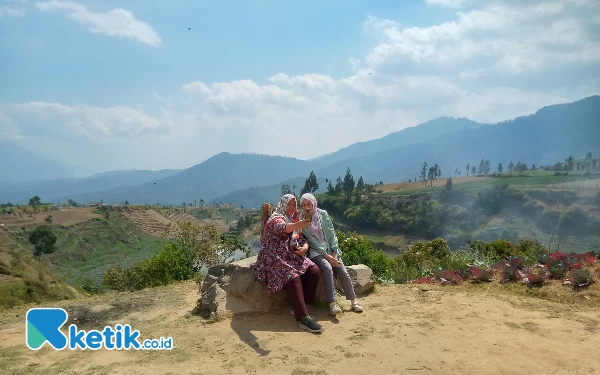 Thumbnail Pengunjung berfoto dengan latar belakang keindahan Bukit Brakseng yang menawan.(Foto: Sholeh/ketik.co.id)