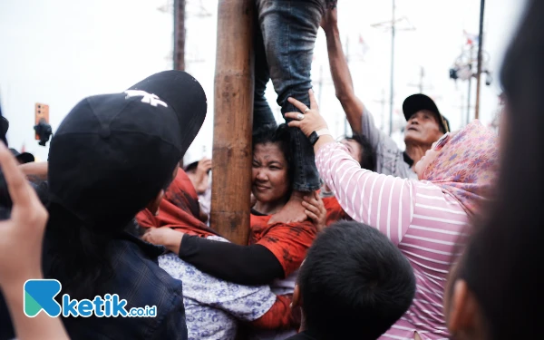 Thumbnail Warga lain termasuk juga para ibu ikut beramai-ramai membantu peserta panjat pinang perempuan yang kesulitan. (Foto: Wisnu Akbar Prabowo/Ketik.co.id)